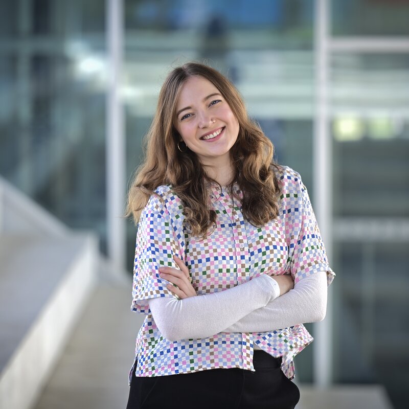 Kerstin Kokoska/FUNKE Foto Services | © Theresa Althaus lächelnd vor einem Glasgebäude.