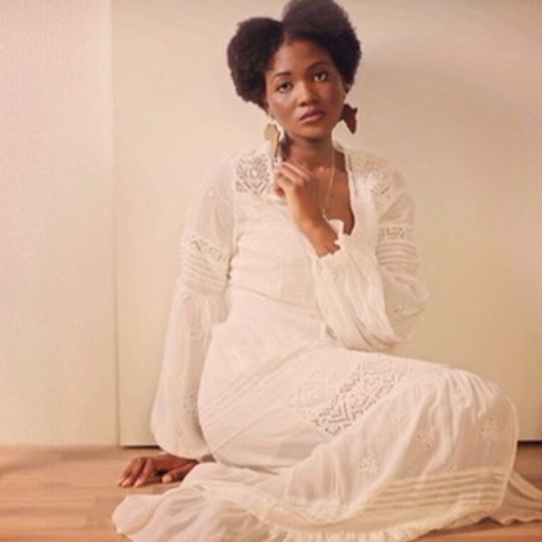 Sanata Doumbia-Milkereit sitzend im weißen Kleid  | © Claus Bergmann