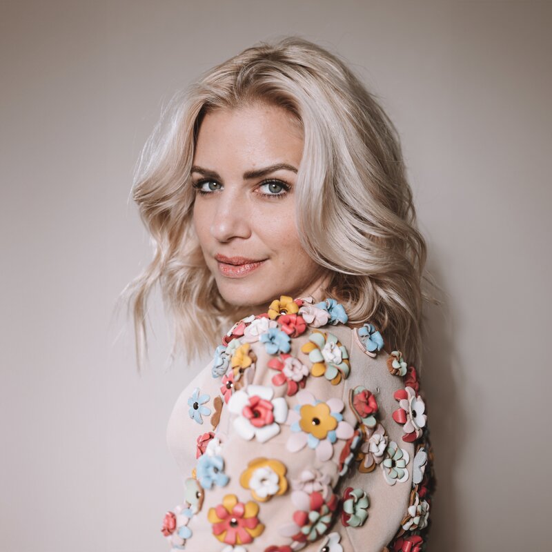 Susan Sideropoulos steht vor einem Fotowand und lächelt | © Liesa Fuchs