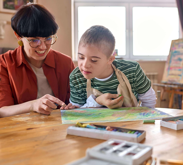 Eine Frau und ein Kind, die gemeinsam an einem Tisch malen.  | © Getty Images | mediaphotos