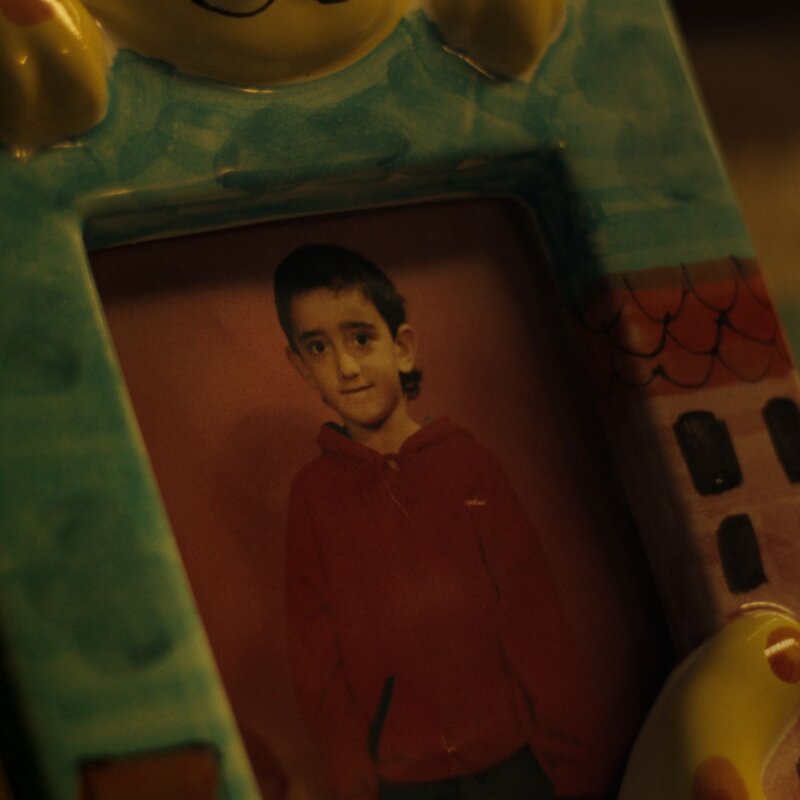 Ein bunt gerahmtes Foto. Es zeigt Aykut Anhan als kleinen Jungen. | © Ein bunt gerahmtes Foto zeigt Aykut Anhan als Kind. © Netflix