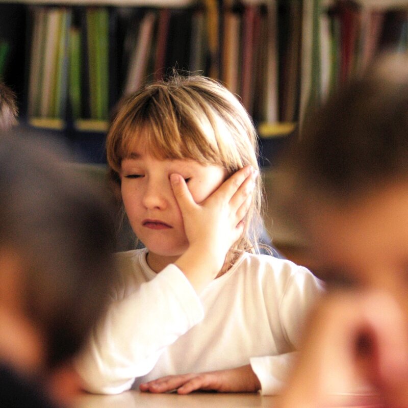 Kind sitzt erschöpft im Klassenzimmer, kann sich nicht mehr auf den Frontalunterricht konzentrieren.  | © IMAGO | photothek