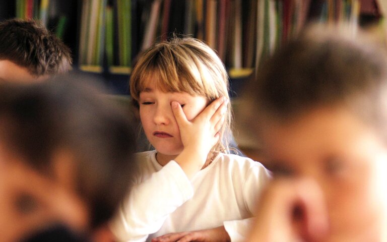 Kind sitzt erschöpft im Klassenzimmer, kann sich nicht mehr auf den Frontalunterricht konzentrieren.  | © IMAGO | photothek
