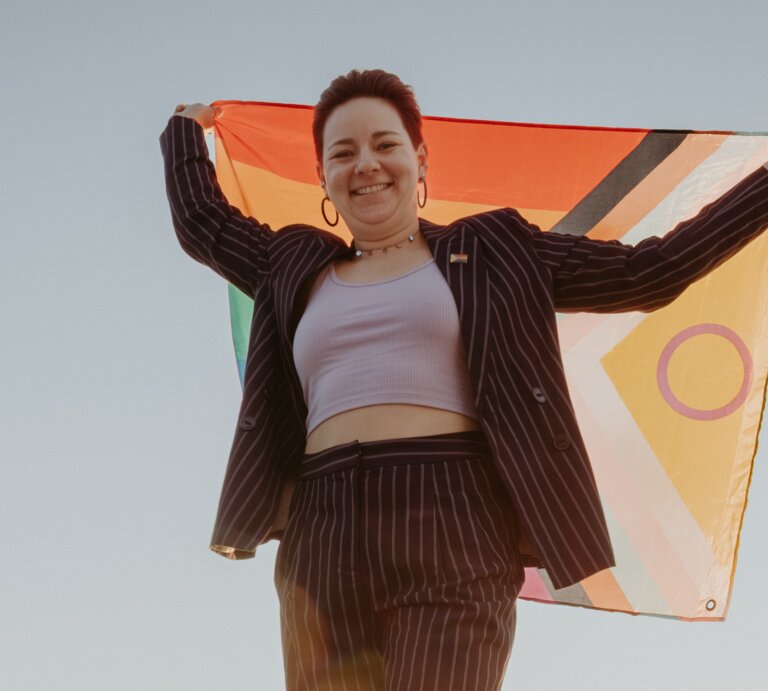 Trauerbegleiterin Caro Zündorf hält eine Pride-Flagge hoch | © Jana Sauer Weddings