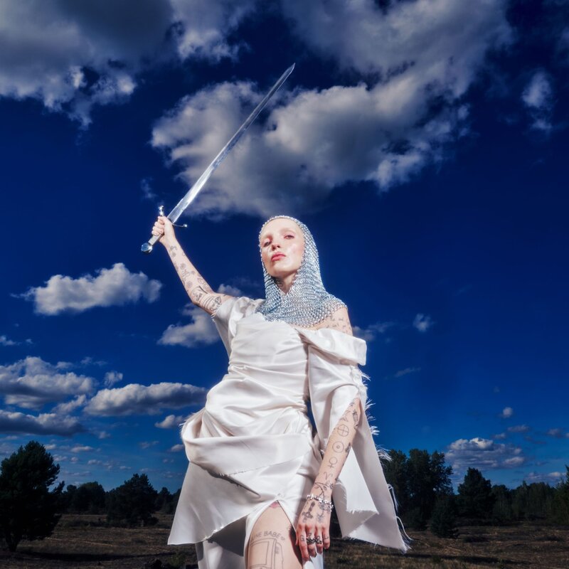 Mia Morgan trägt ein weißes Kleid und eine Kettenhaube und hält ein Schwert über ihren Kopf. | © Foto: Can Wagener