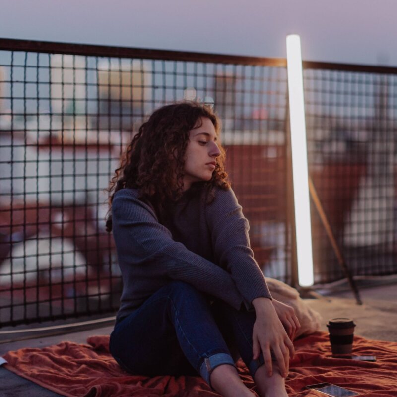 Unhappy young woman resting and sitting on the roof with city view. An unhappy young woman resting and sitting on the roof with city view. | © Foto: IMAGO | HalfPoint Images