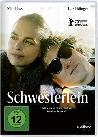 Die Schauspieler*innen Nina Hoss und Lars Eidinger sitzen in einem Auto auf der Rückbank, er tränkt eine Sonnenbrille und legt seinen Kopf auf ihre Schulter. Sie schaut zum Fenster hinaus. „Schwesterlein“