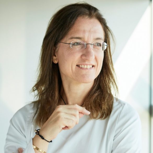 Kerstin Wagner, HR-Chefin der Deutschen Bahn, weißes Oberteil vor weißem Hintergrund, blickt schräg links an Kamera vorbei aus dem Fenster. Sie trägt eine Brille und braunes Haar.
