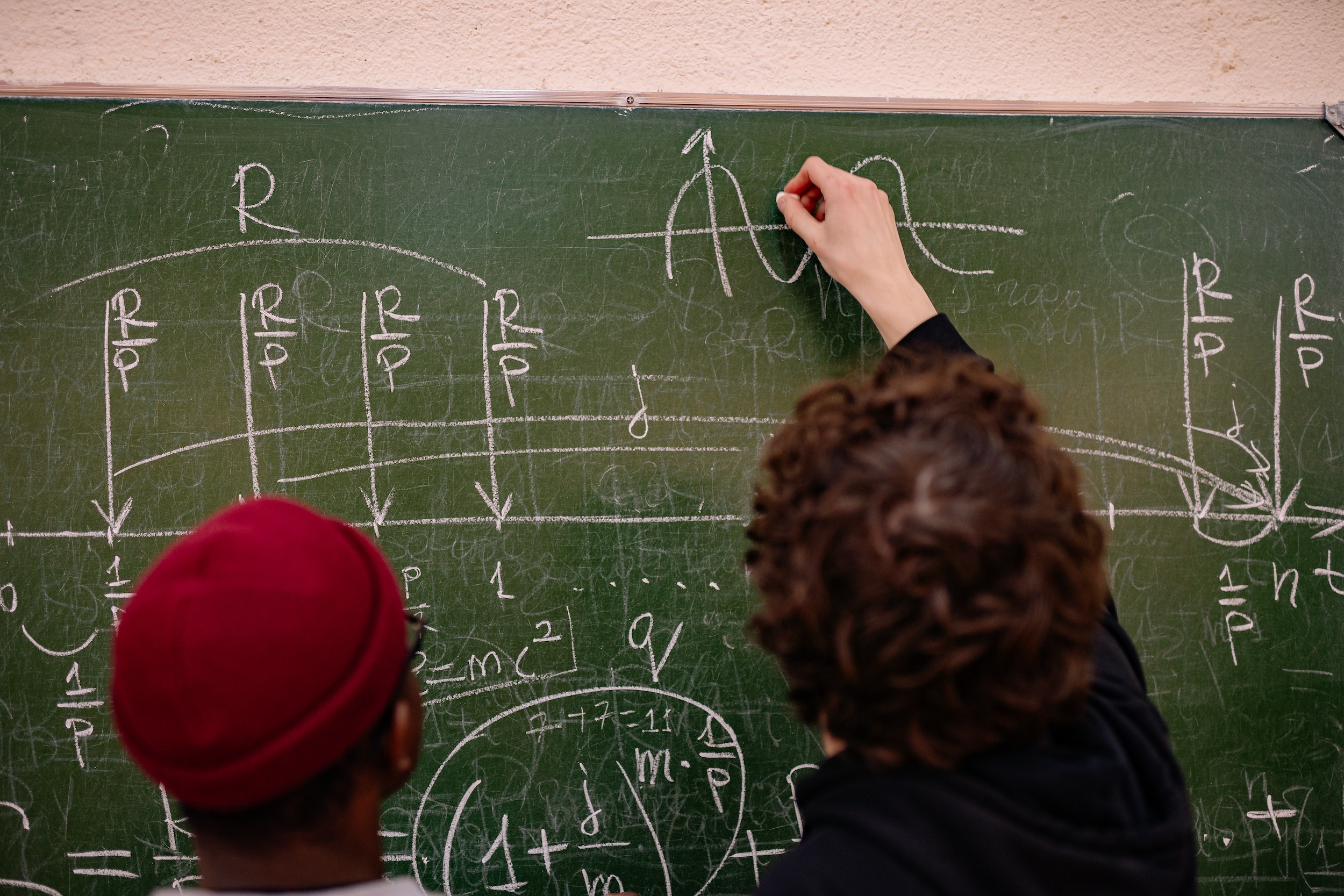 Zwei Schüler stehen an der Tafel und lösen Aufgaben im Bereich Naturwissenschaften.