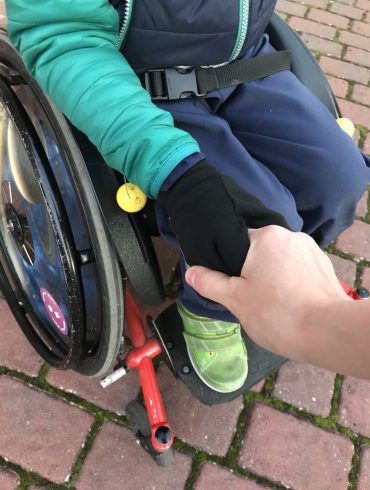 Der Sohn unserer Autorin Jennifer Meyer-Ueding. Mutter und Sohn, der im Rollstuhl mobil ist, halten sich die Hand.