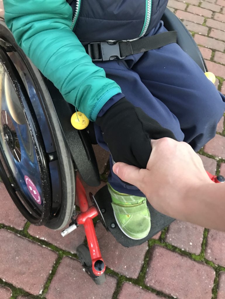 Der Sohn unserer Autorin Jennifer Meyer-Ueding. Mutter und Sohn, der im Rollstuhl mobil ist, halten sich die Hand.