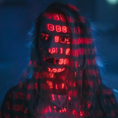 Frau im rötlichen Schatten, auf ihr sind digitale Codes zu sehen, Person als Projektionsfläche