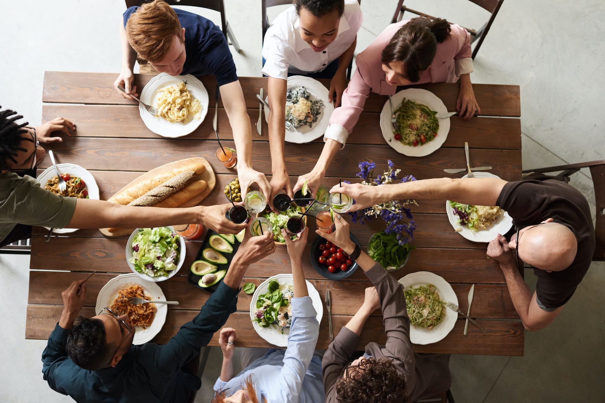 Viele Menschen essen gemeinsam und stoßen an. Gespräch und Abendessen unter Freund*innen.