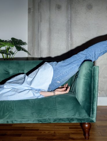 Frau liegt erschöpft auf einem Sofa