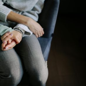 Frau und Kind sitzen nebeneinander, wartend. Man sieht ihre Gesichter nicht.