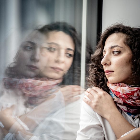 Die Journalistin Heba Alkadri blickt gedankenverloren aus dem Fenster. Ihr Gesicht spiegelt sich in der Scheibe.