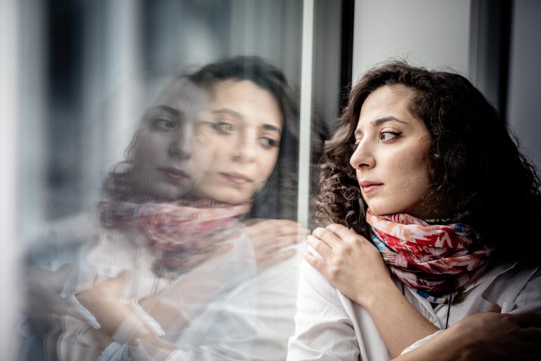 Die Journalistin Heba Alkadri blickt gedankenverloren aus dem Fenster. Ihr Gesicht spiegelt sich in der Scheibe.