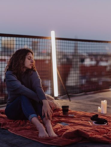 Unhappy young woman resting and sitting on the roof with city view. An unhappy young woman resting and sitting on the roof with city view.