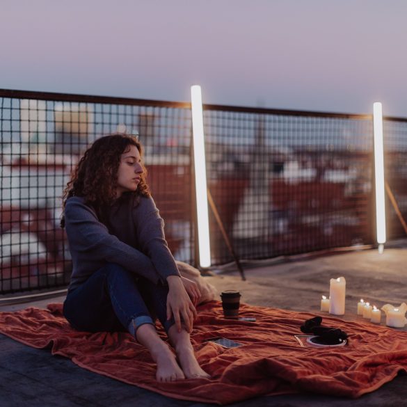 Unhappy young woman resting and sitting on the roof with city view. An unhappy young woman resting and sitting on the roof with city view.