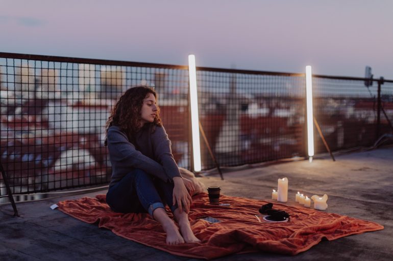 Unhappy young woman resting and sitting on the roof with city view. An unhappy young woman resting and sitting on the roof with city view.