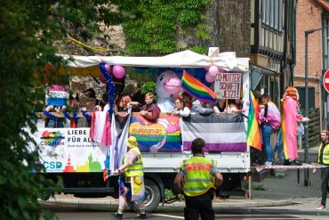 Wagen mit Pride-Besucher*innen fährt durch Wernigerode. Es ist bunt, aber weniger bunt als in den letzten Jahren, weil die Bedrohungslage größer ist.