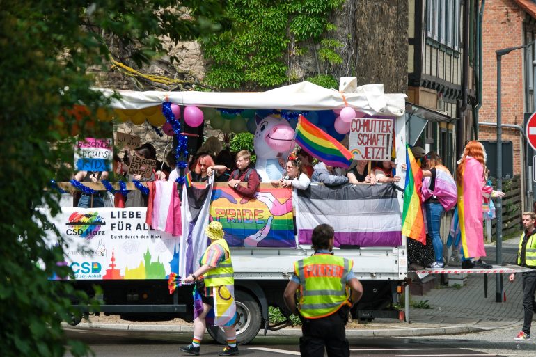 Wagen mit Pride-Besucher*innen fährt durch Wernigerode. Es ist bunt, aber weniger bunt als in den letzten Jahren, weil die Bedrohungslage größer ist.
