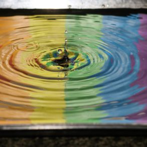 Regenbogenflagge spiegelt sich in Pfütze.