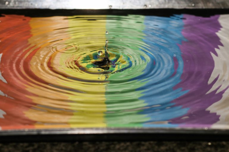 Regenbogenflagge spiegelt sich in Pfütze.